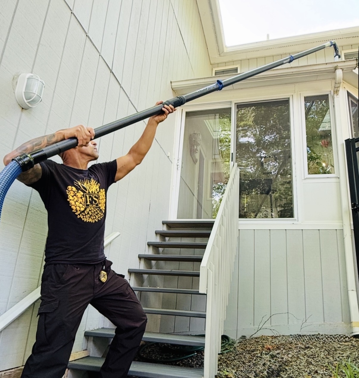 Four Seasons team member using a long-reach gutter vacuum to clean a home’s gutters